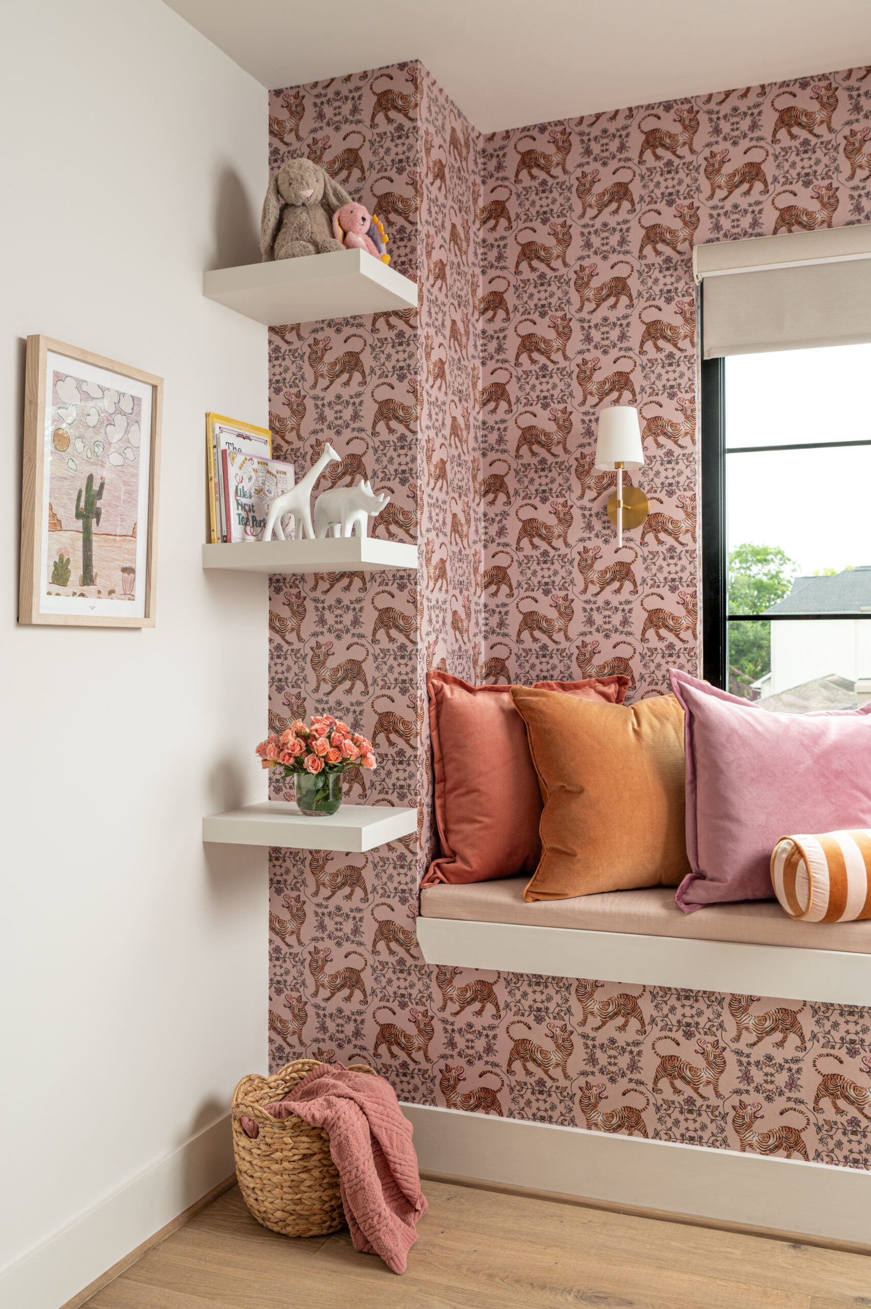 A children’s reading corner with patterned wallpaper, satin and velvet cushions, and soft plush toys