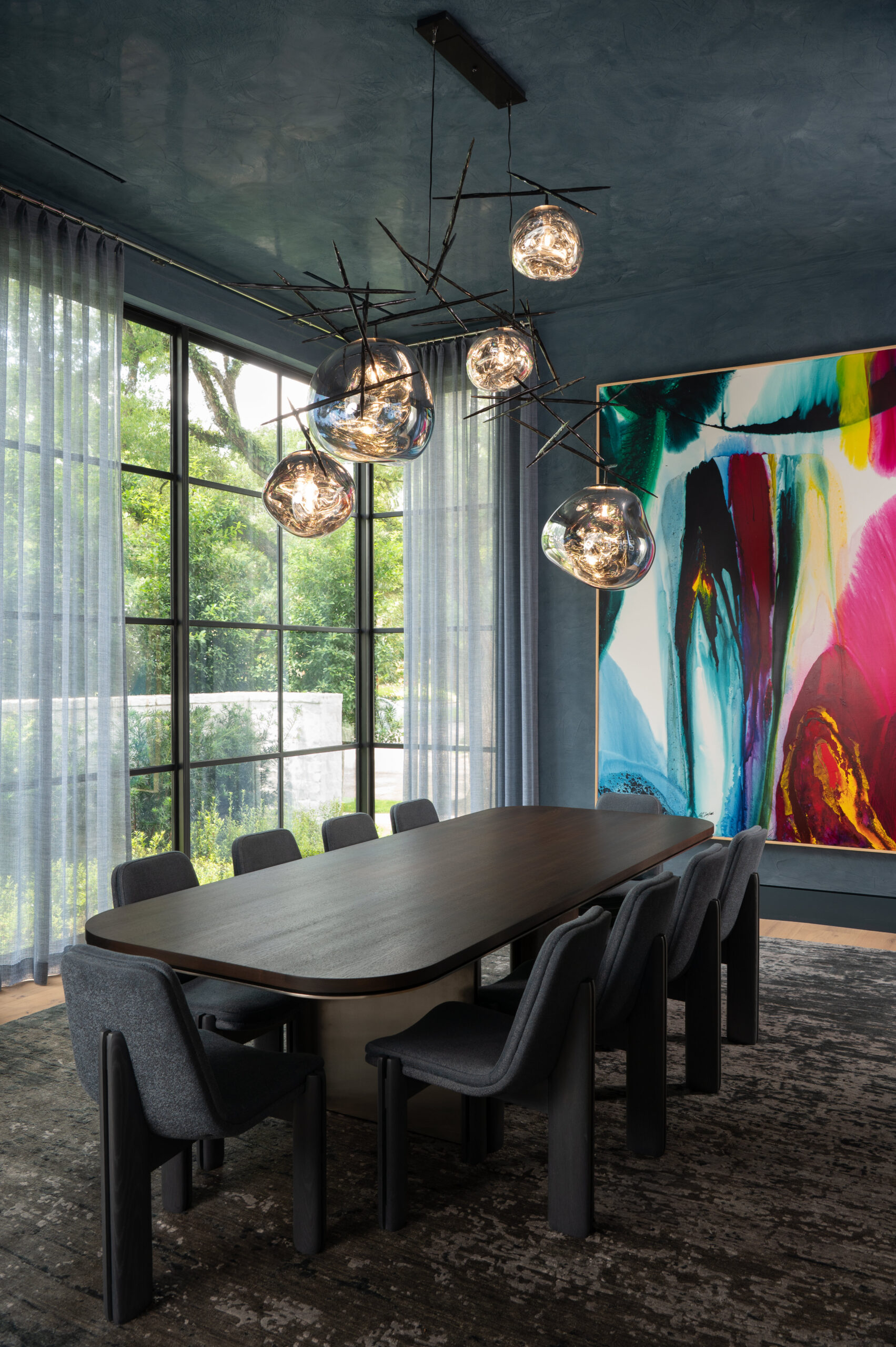 Elegant dining room with bold abstract art and moody blue walls, using color in interior design to create contrast, drama, and sophistication.