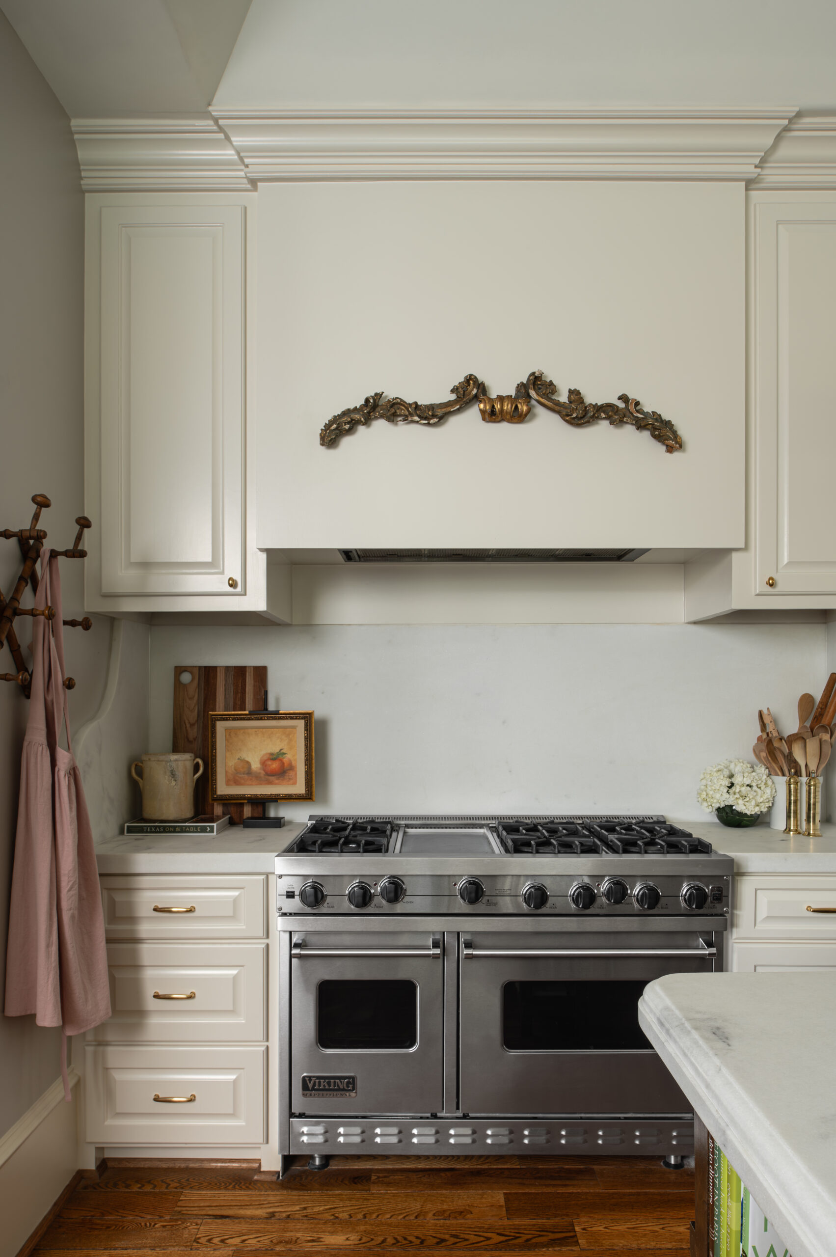 A front-facing shot of the stainless steel Viking range, custom cabinetry, and antique-style trim detail above the hood vent, blending modern function with heirloom charm.