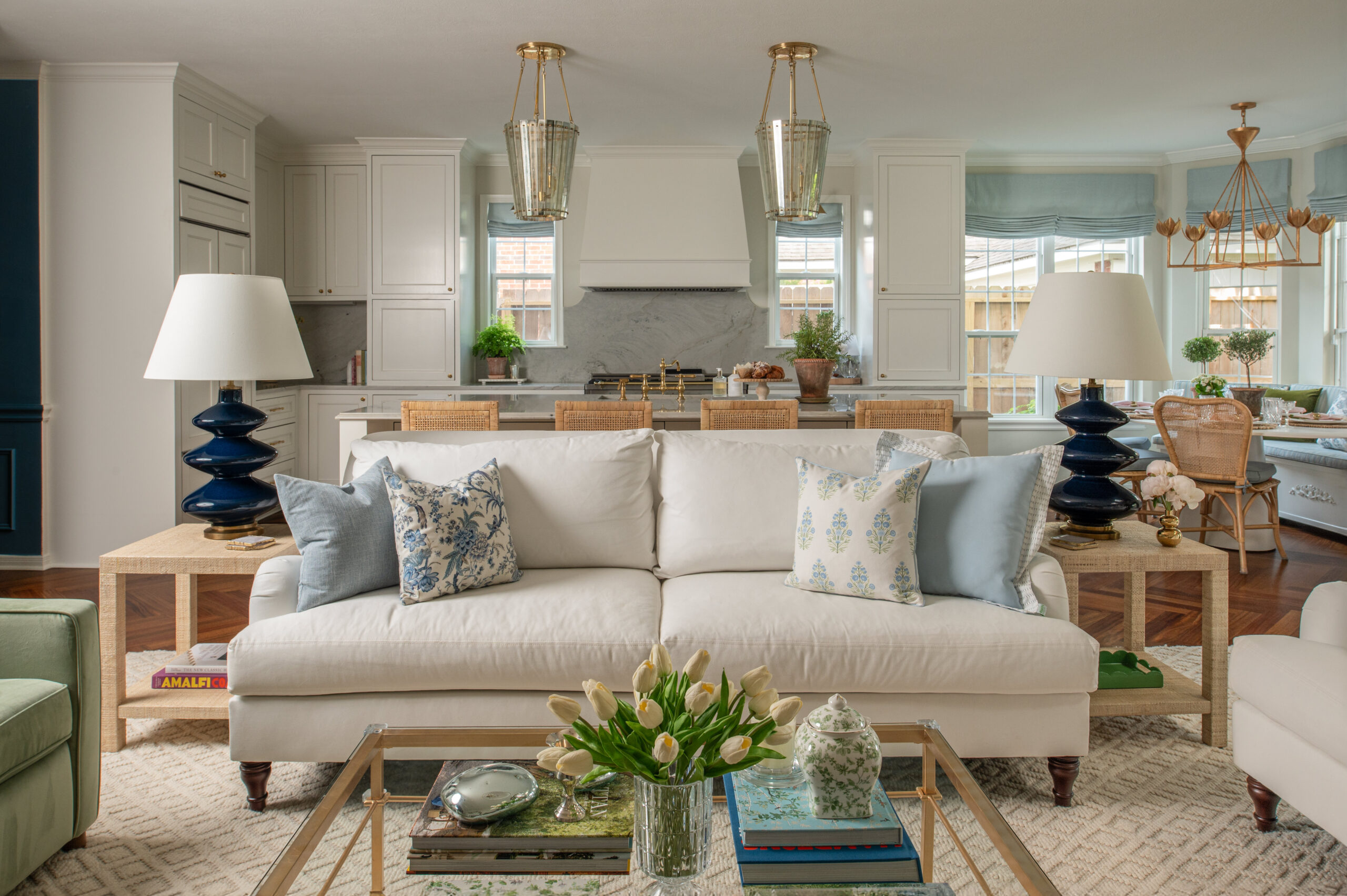 Open-concept living and kitchen space captured in these home renovation photos, featuring twin white sofas, curated coffee table styling, and a backdrop of custom cabinetry.
