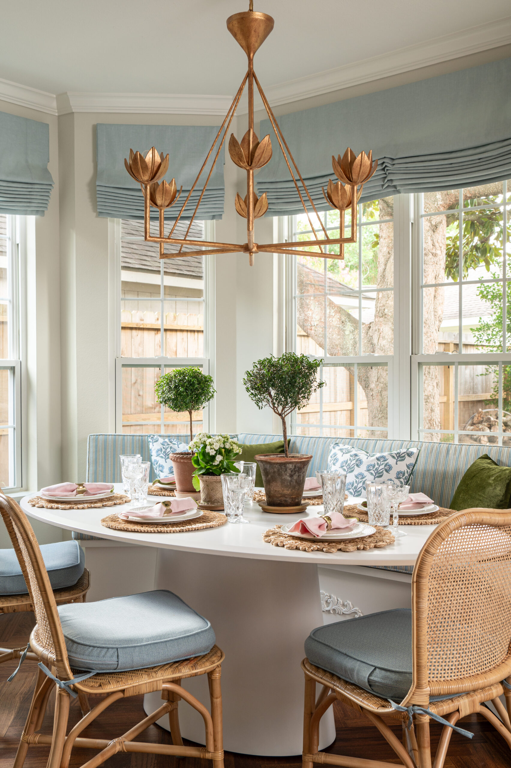 Styled breakfast nook with rattan chairs, floral pillows, and layered greenery, captured during a home renovation photos session.