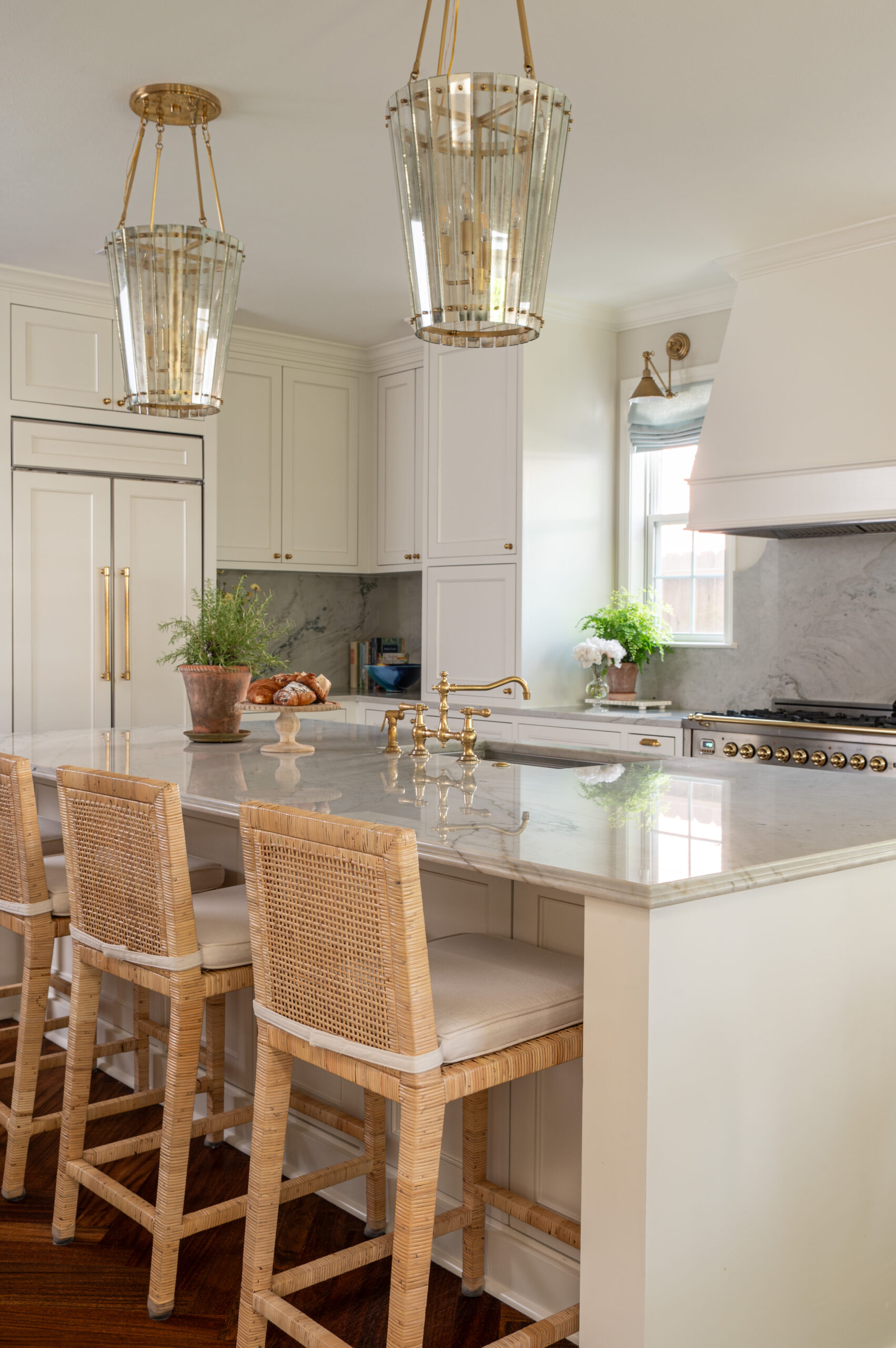 Close-up of the kitchen island with rattan bar stools and brass fixtures, a highlight of these home renovation photos showcasing timeless, functional design.