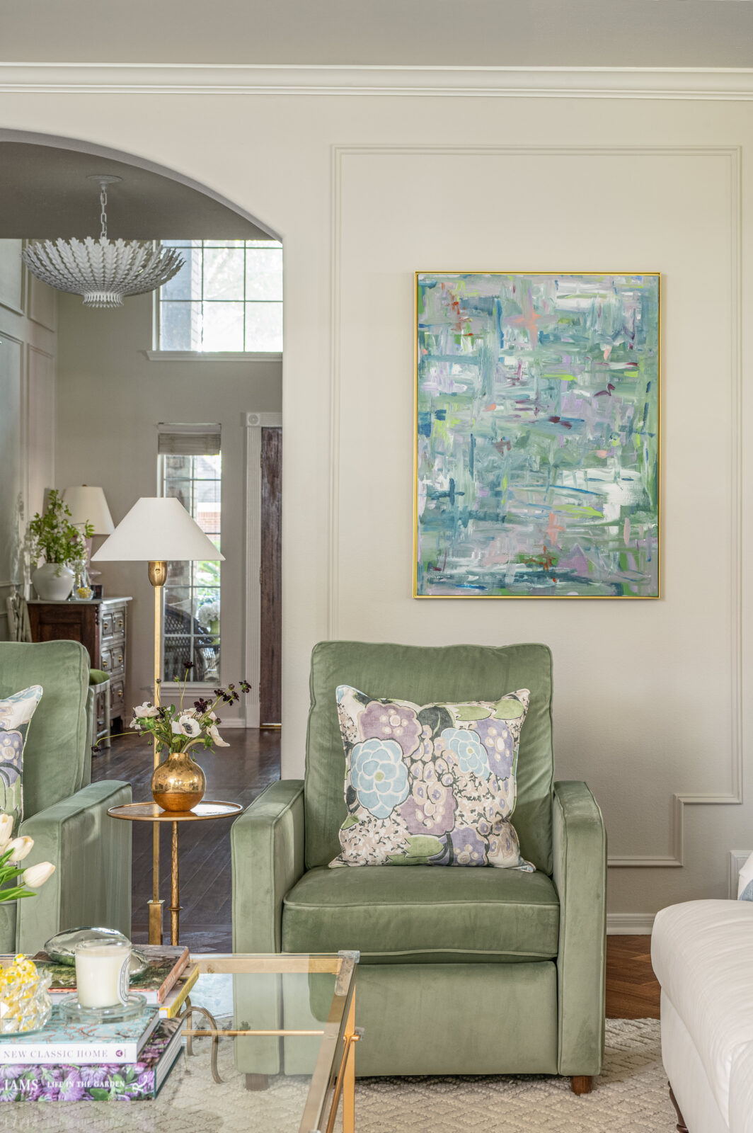 Cozy corner featuring a green velvet armchair, floral pillow, and abstract pastel artwork—a perfect detail from recent home renovation photos.